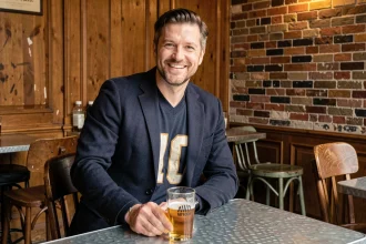 Homme en blazer marine sur maillot de foot vintage dans un bistro parisien, illustrant le style bauf chic assumé