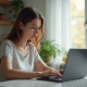 Jeune femme utilisant un ordinateur dans une cuisine lumineuse